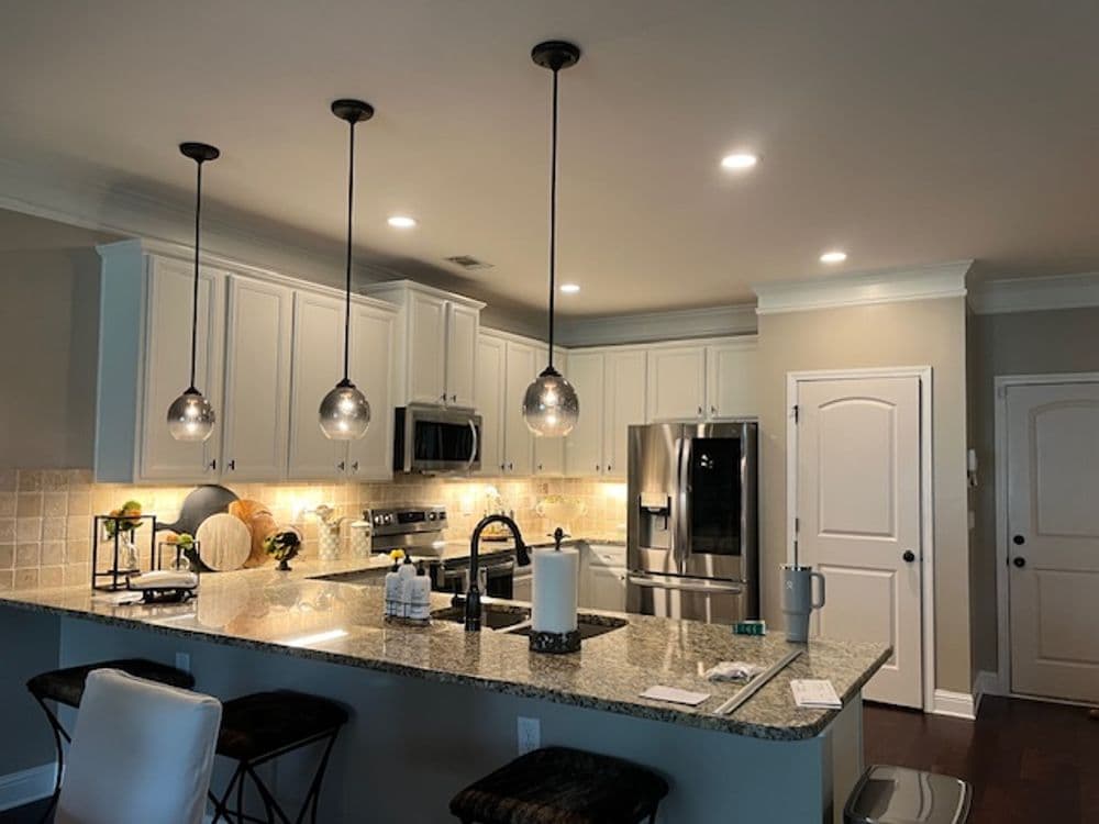 Modern kitchen with granite countertops, pendant lights, and stainless steel appliances.