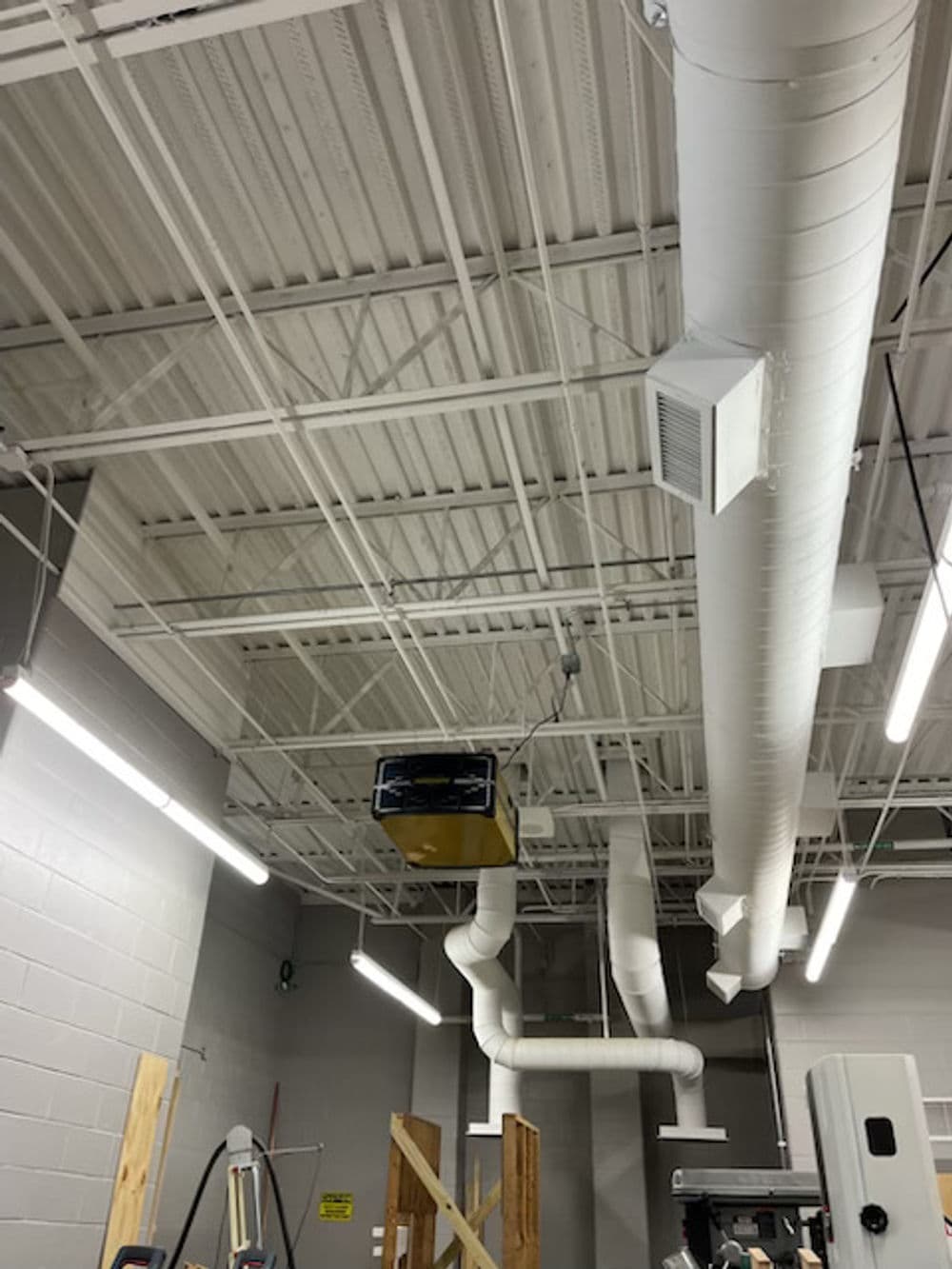 Industrial workspace with exposed ceiling, ducts, and overhead lighting.