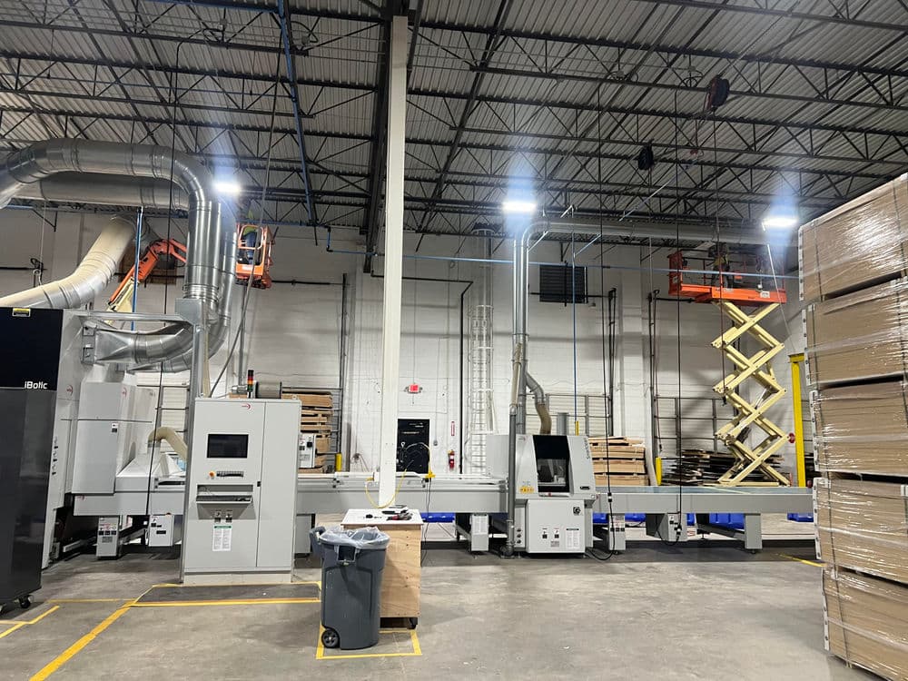 Industrial machinery in a warehouse with conveyors, lift equipment, and storage pallets.
