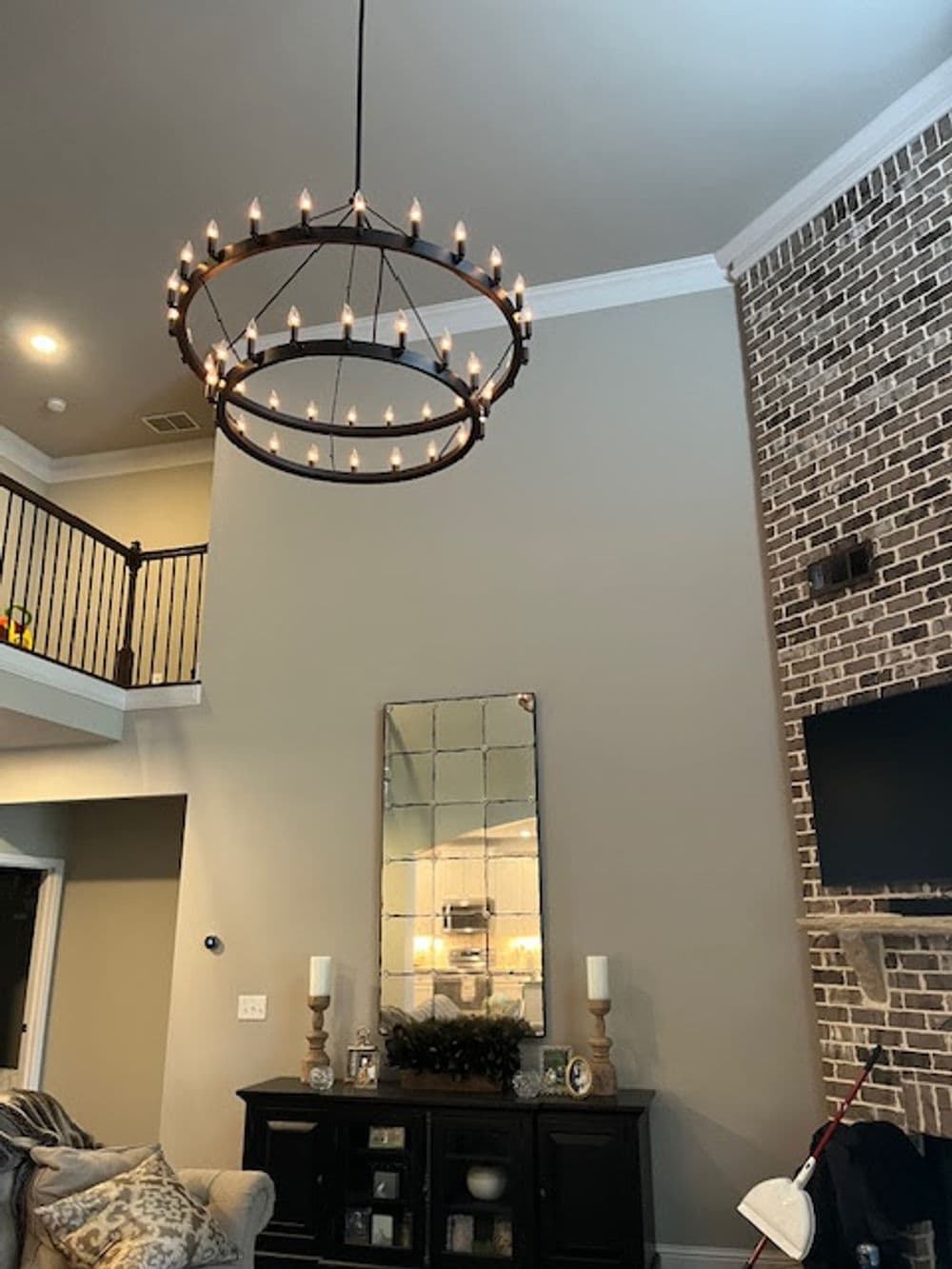 Modern chandelier with candles illuminating a stylish living room with brick wall.