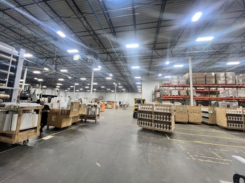 Spacious warehouse interior with shelves, boxes, and forklifts in operation.