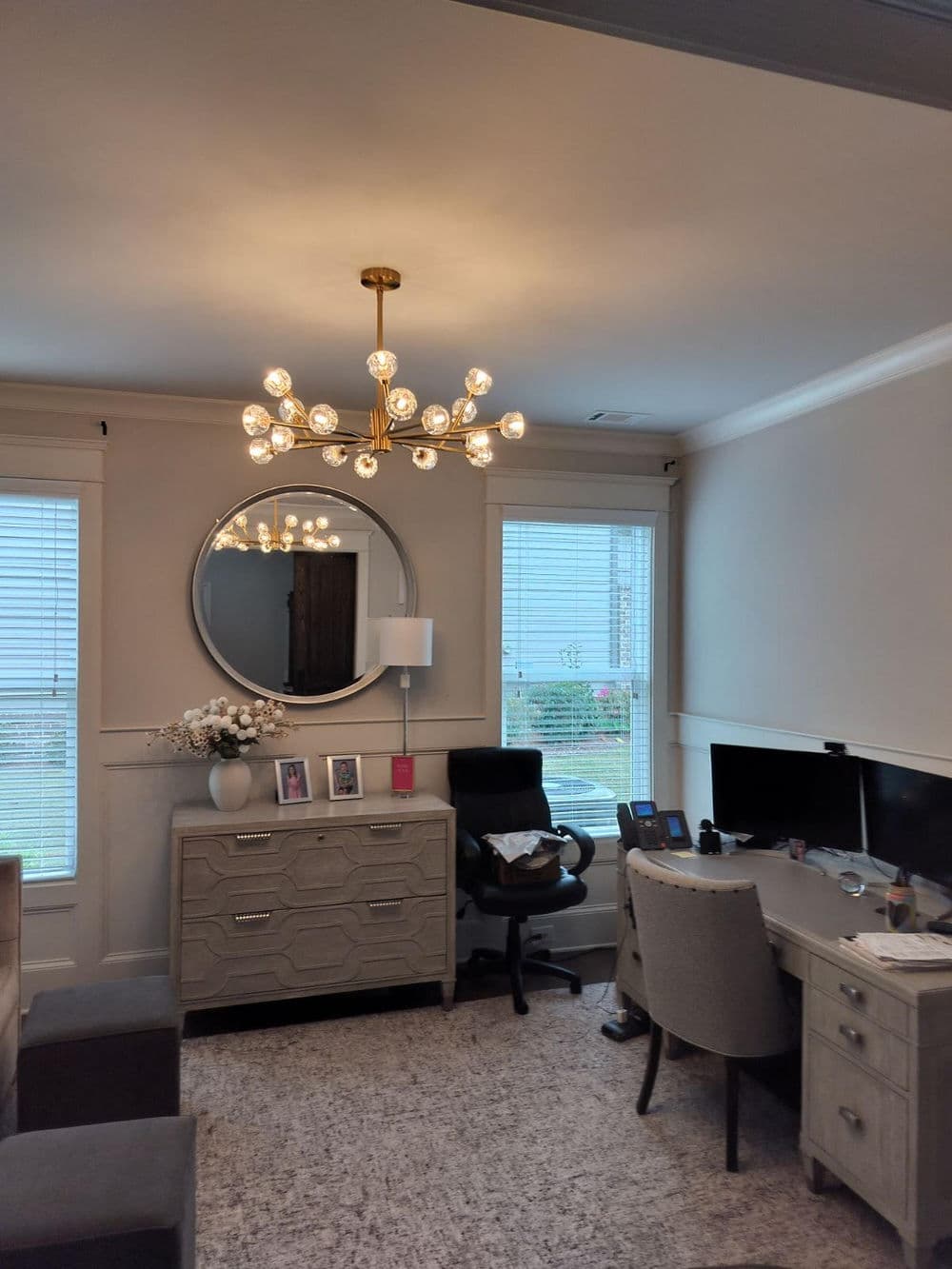 Modern home office featuring a stylish chandelier, desk, and elegant decor.