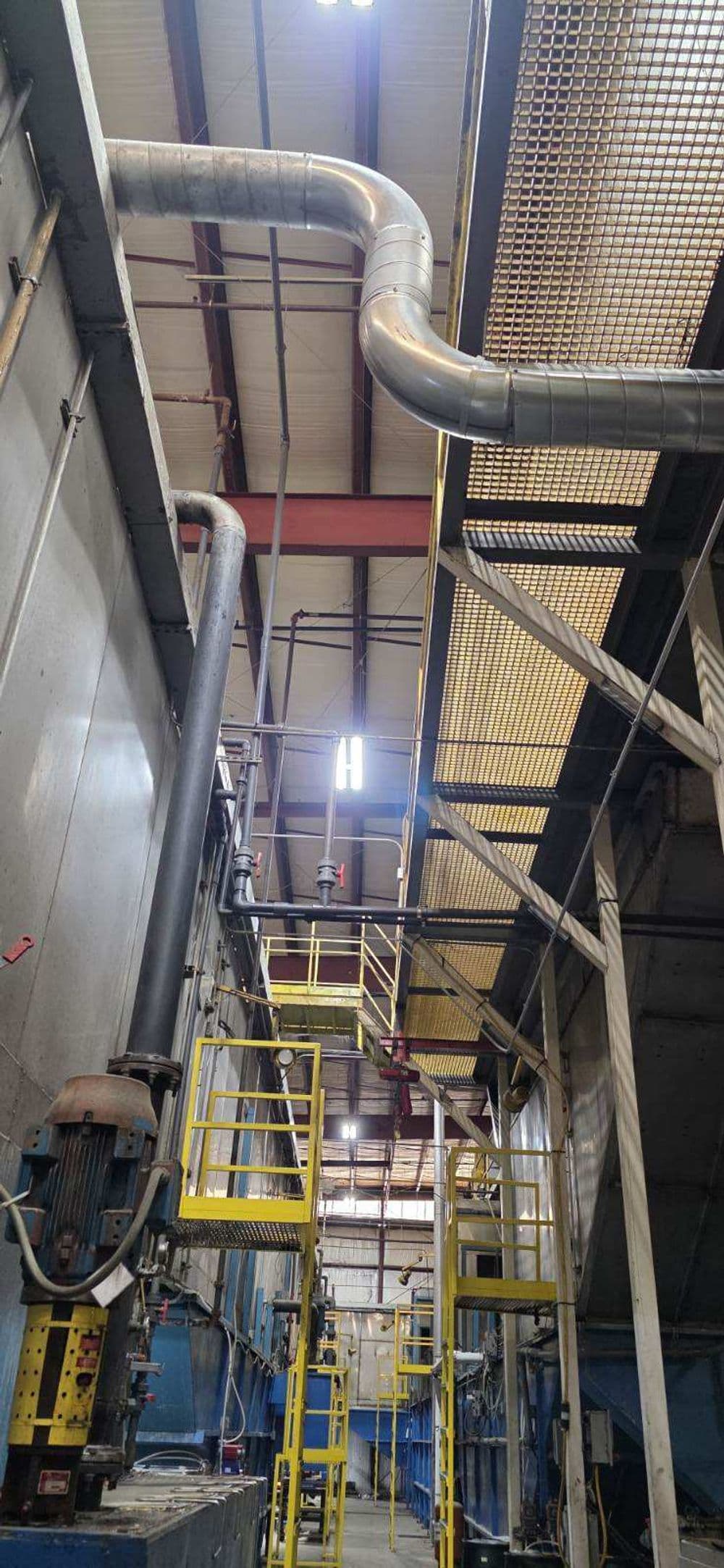 Industrial facility interior with piping, metal stairs, and machinery highlighted.