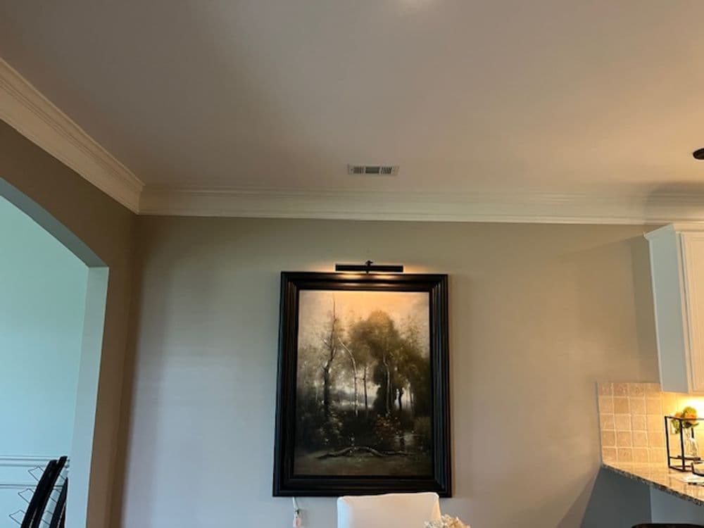 Elegant dining room featuring a large framed landscape painting on a light beige wall.