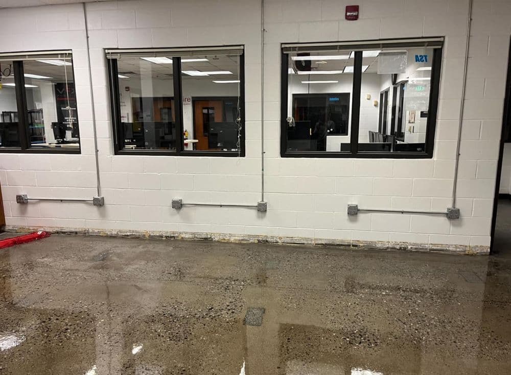 Interior view of a commercial space with polished concrete floor and utility connections on walls.
