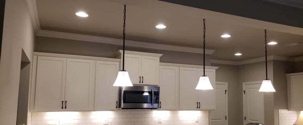 Modern kitchen with white cabinets, pendant lighting, and stainless steel microwave.