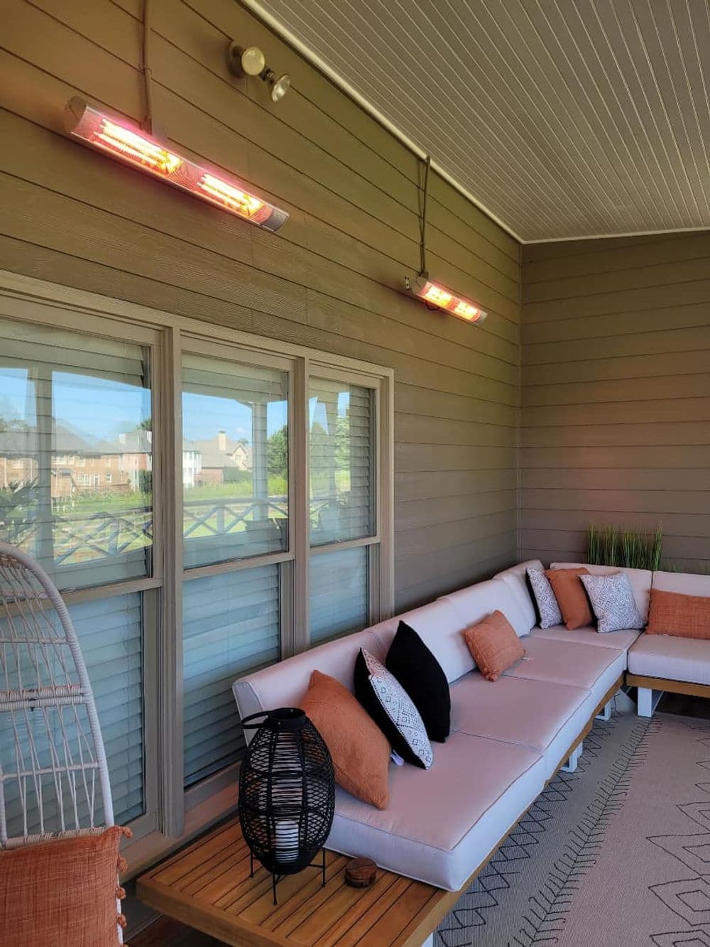 Stylish outdoor patio with infrared heaters, modern seating, and cozy decor accents.
