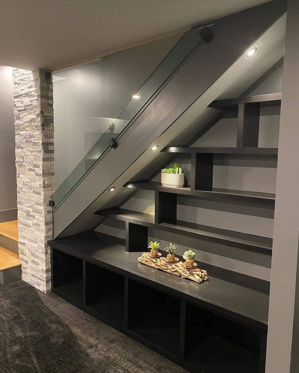 Modern interior staircase with glass railing and decorative shelving showcasing plants.