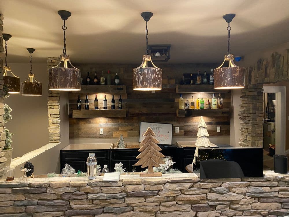 Cozy bar with stone wall, festive decorations, and warm pendant lighting.