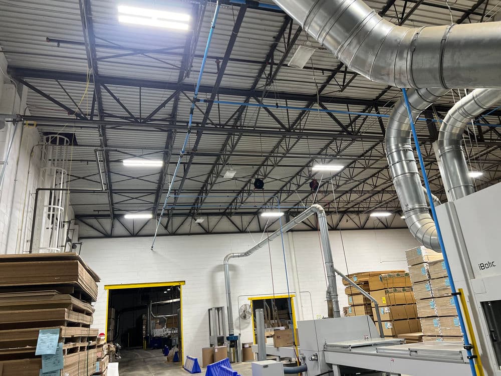 Warehouse interior with industrial ventilation, shelving, and loading dock entrance.