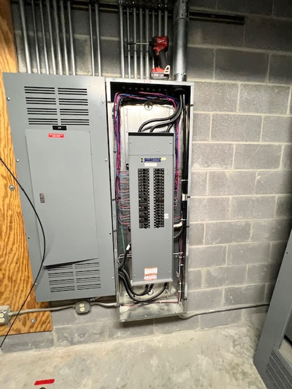 Electrical panel with multiple circuits and wiring in a basement setting.