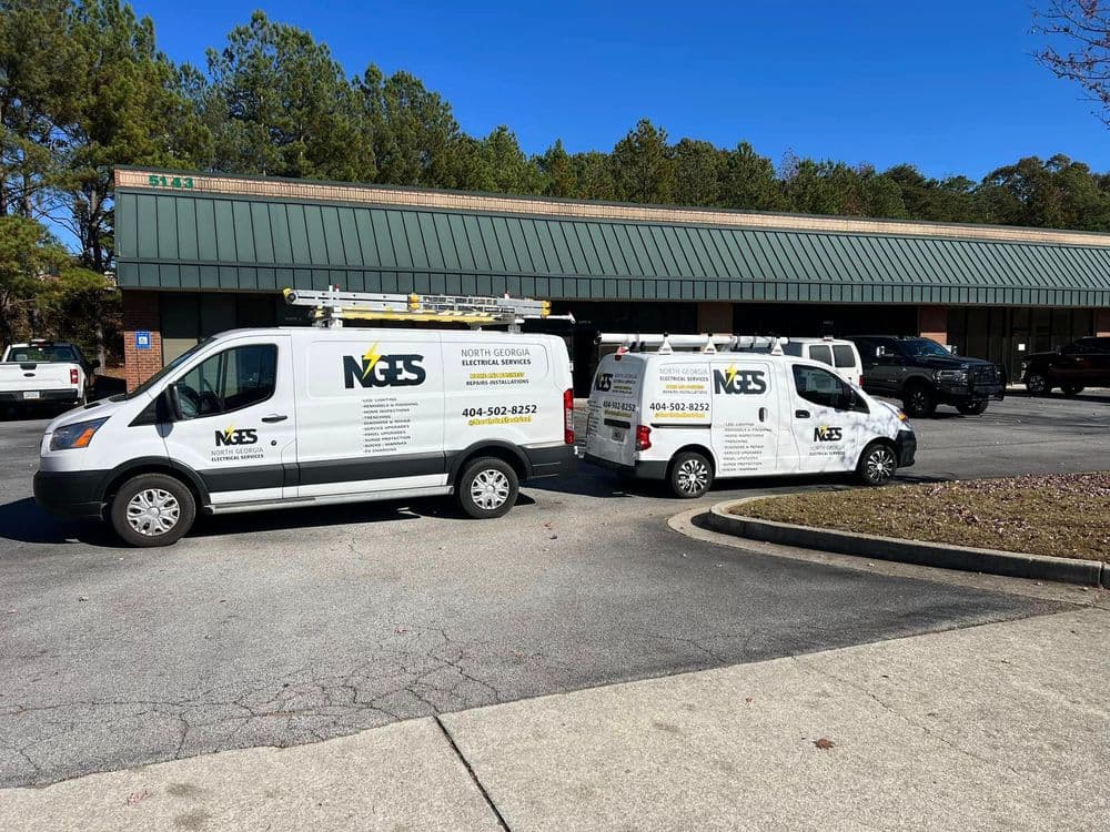 Two North Georgia Electrical Services vans parked outside a retail store on a sunny day.