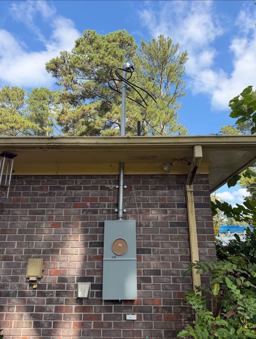 Utility meter on brick building with trees and clear blue sky in the background.