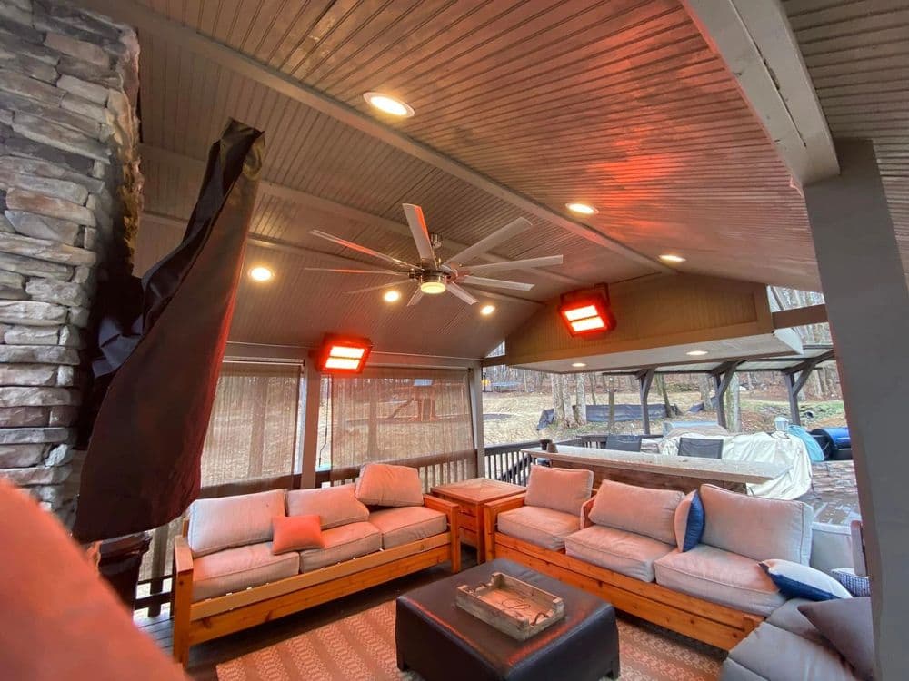 Cozy outdoor living space with stone accents, ceiling fan, and heated seating area.